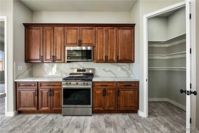 kitchen featuring light wood finished floors, appliances with stainless steel finishes, and tasteful backsplash