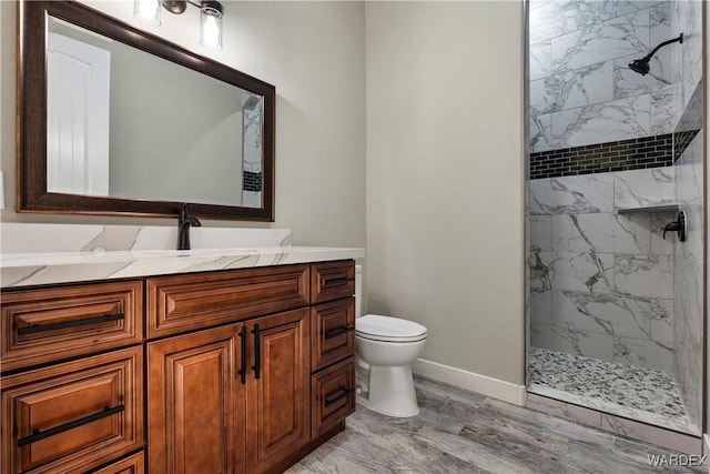 full bath with toilet, a marble finish shower, baseboards, and vanity