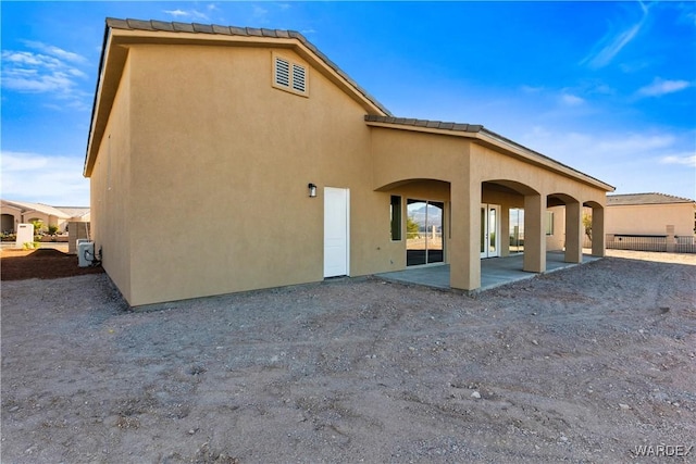 back of property with a patio and stucco siding