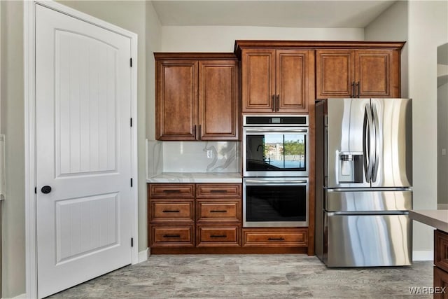 kitchen featuring stainless steel appliances, brown cabinets, light countertops, and decorative backsplash