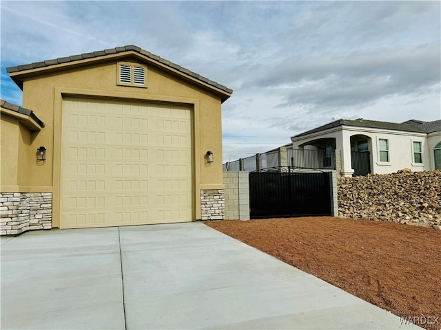 garage featuring driveway, a gate, and visible vents