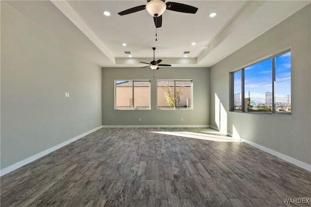 unfurnished room featuring dark wood-style floors, recessed lighting, a raised ceiling, and baseboards