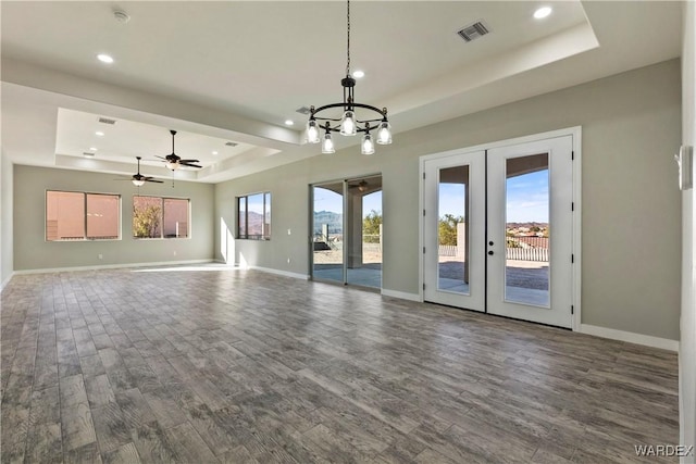 unfurnished living room with baseboards, visible vents, a raised ceiling, dark wood-style flooring, and french doors