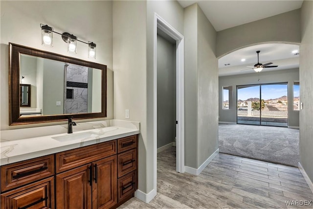 bathroom featuring a ceiling fan, vanity, baseboards, and wood finished floors