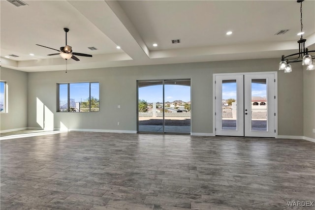 unfurnished living room with a wealth of natural light, french doors, a tray ceiling, and visible vents