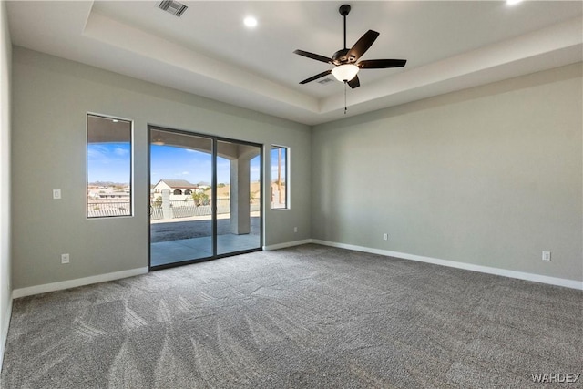 unfurnished room with baseboards, visible vents, a raised ceiling, ceiling fan, and carpet flooring