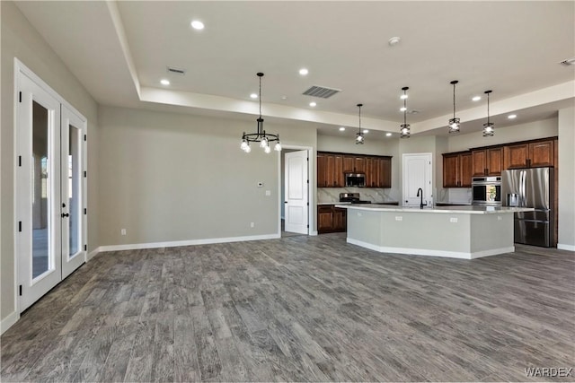 kitchen with a center island with sink, pendant lighting, stainless steel appliances, and open floor plan