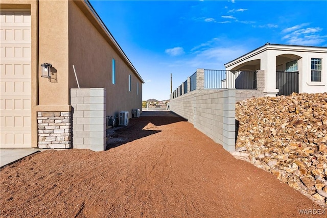 view of home's exterior featuring a garage, central AC, and stucco siding