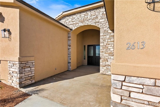 doorway to property with stone siding and stucco siding