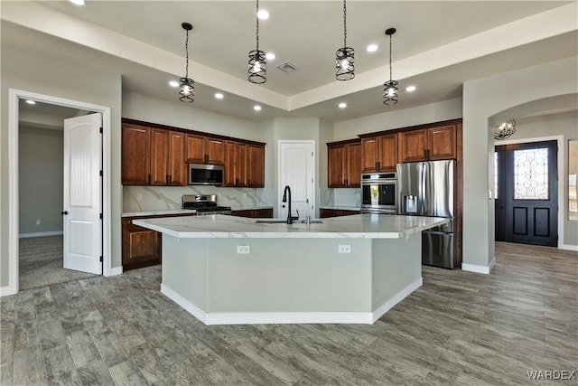 kitchen with a large island, a sink, appliances with stainless steel finishes, and pendant lighting