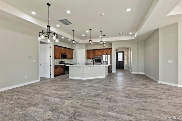 kitchen featuring appliances with stainless steel finishes, open floor plan, visible vents, and a center island with sink