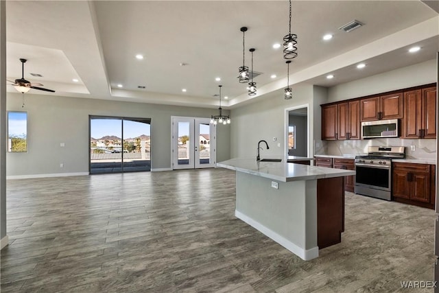 kitchen with stainless steel appliances, a tray ceiling, and open floor plan