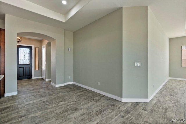 entrance foyer with baseboards, arched walkways, and wood finished floors