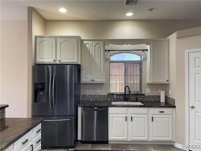 kitchen with white cabinets, dark stone countertops, stainless steel appliances, a sink, and recessed lighting