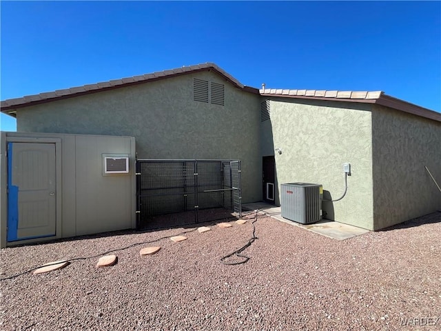 back of property with stucco siding and central air condition unit