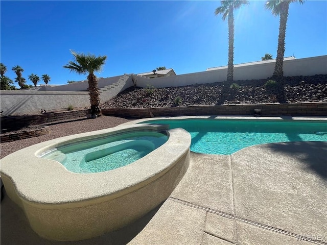 view of swimming pool with a fenced backyard and a pool with connected hot tub