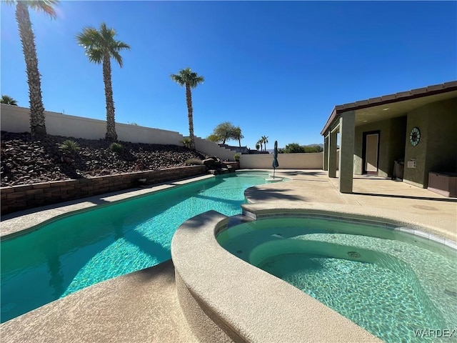 view of swimming pool with a fenced backyard, a pool with connected hot tub, and a patio