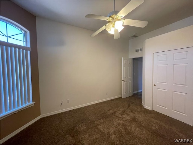 unfurnished bedroom with dark colored carpet, a ceiling fan, visible vents, and baseboards