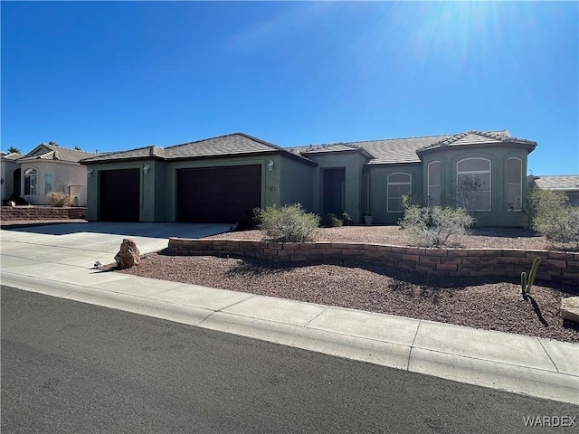 view of front of home with concrete driveway, an attached garage, and stucco siding