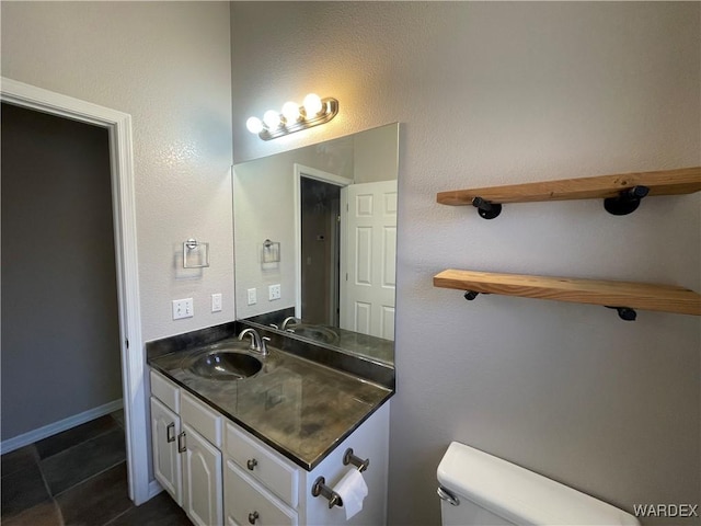 bathroom featuring tile patterned flooring, vanity, toilet, and baseboards