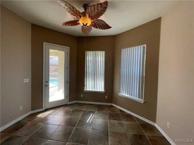 entryway featuring ceiling fan, baseboards, and dark tile patterned flooring