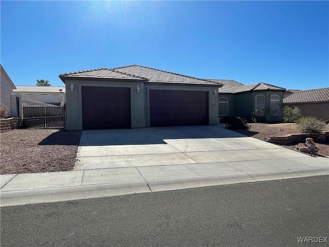 view of front of house featuring concrete driveway, a tiled roof, an attached garage, and stucco siding