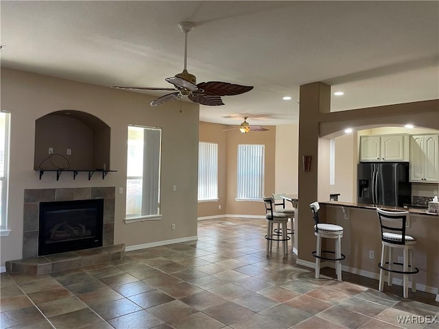 kitchen featuring dark countertops, a breakfast bar area, open floor plan, and black fridge