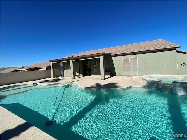 view of swimming pool with a pool with connected hot tub, a patio area, and fence