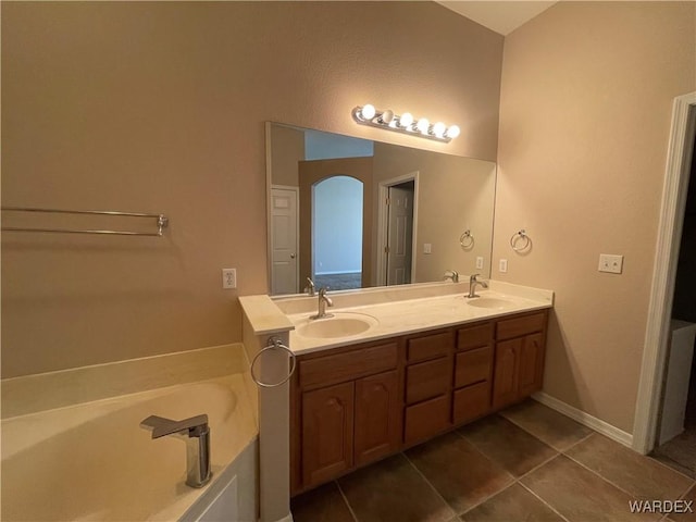 full bathroom with double vanity, a sink, a bath, and tile patterned floors