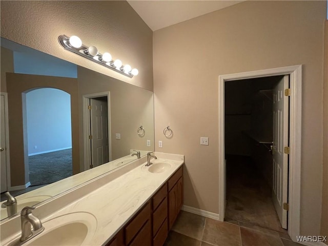 full bathroom featuring double vanity, vaulted ceiling, a sink, and tile patterned floors