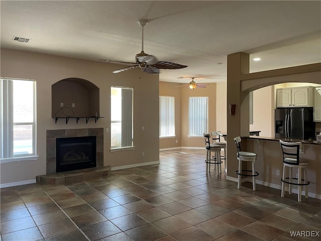 living room with baseboards, visible vents, ceiling fan, dark tile patterned floors, and a fireplace