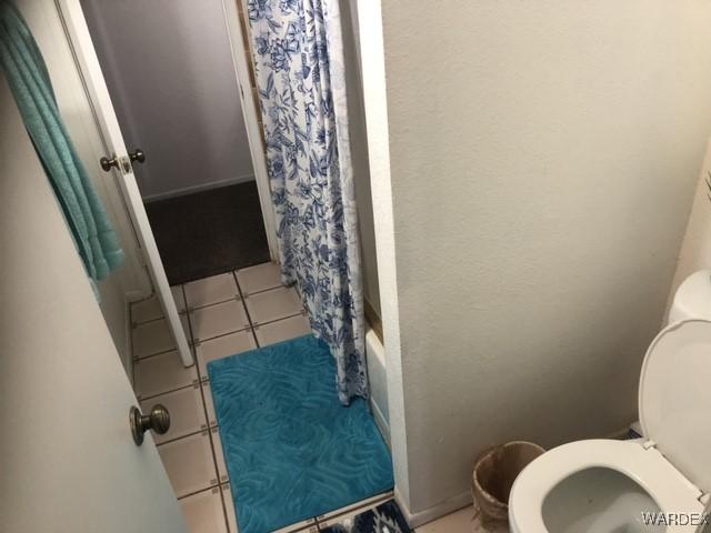 full bathroom featuring toilet, tile patterned flooring, and shower / bath combo with shower curtain