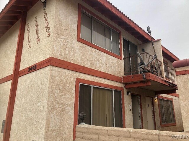 view of side of property featuring a balcony and stucco siding