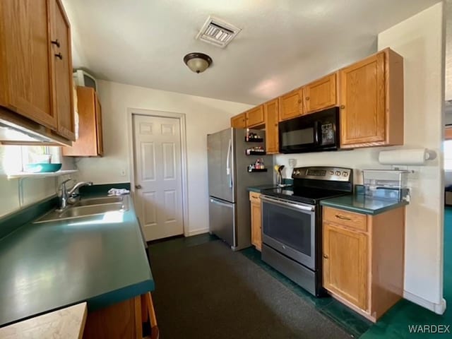 kitchen with appliances with stainless steel finishes, dark countertops, visible vents, and a sink