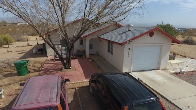 view of front of property with an attached garage, a shingled roof, concrete driveway, and stucco siding