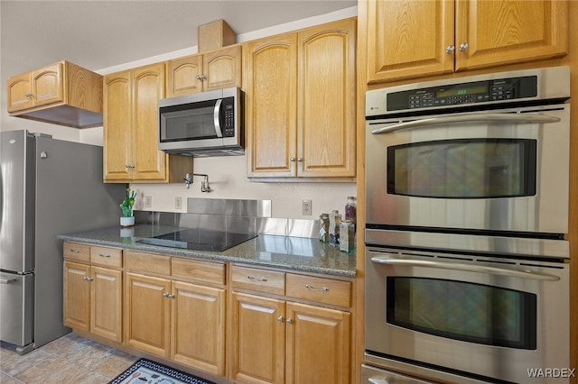 kitchen featuring light tile patterned floors, dark stone countertops, and stainless steel appliances