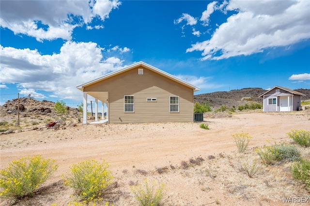 back of house with a shed, an outdoor structure, and central AC