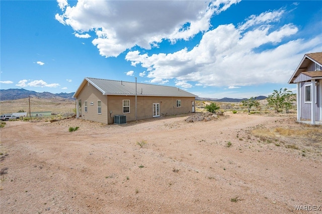 back of property featuring a mountain view, central air condition unit, and metal roof