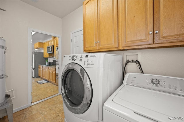 clothes washing area featuring washer and dryer, cabinet space, and baseboards