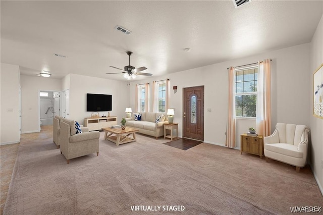 living area featuring visible vents, light colored carpet, baseboards, and a ceiling fan