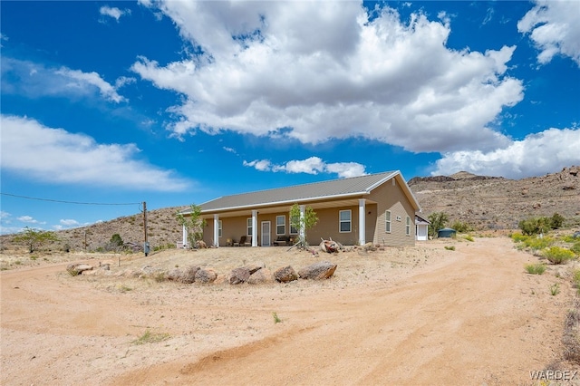 back of house with a porch, a mountain view, and metal roof