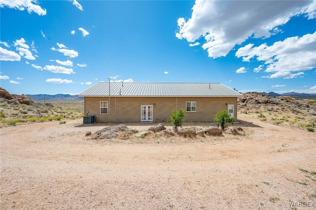 rear view of property with french doors, a mountain view, central AC unit, and metal roof