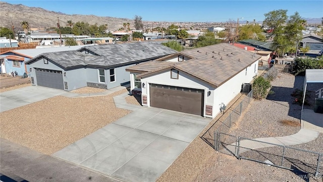 ranch-style home featuring driveway, an attached garage, fence, and stucco siding