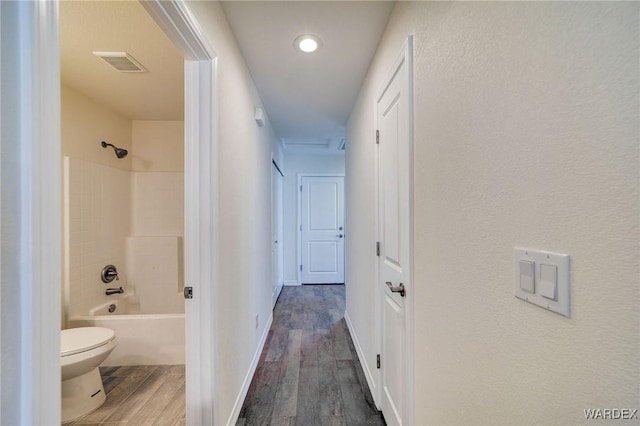 hall featuring dark wood-style flooring, visible vents, and baseboards