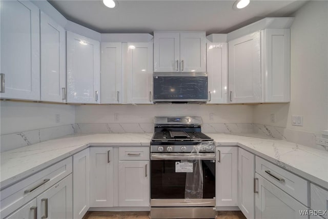 kitchen with light stone countertops, white cabinetry, stainless steel appliances, and recessed lighting