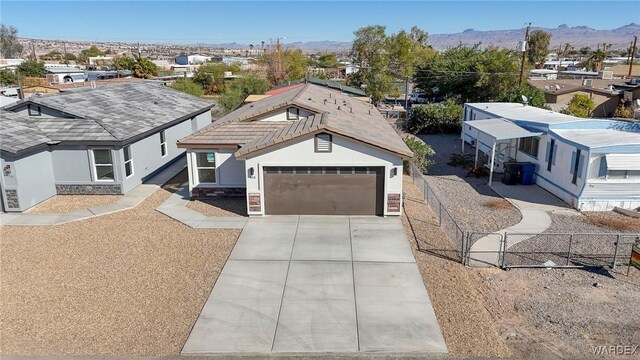 ranch-style home featuring a mountain view, a garage, fence, driveway, and stucco siding