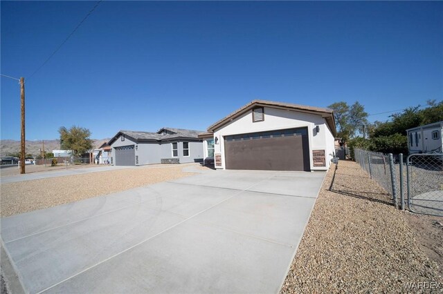 view of front of house featuring a garage, fence, concrete driveway, and stucco siding