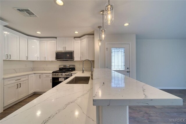 kitchen with stainless steel appliances, a sink, visible vents, and white cabinets