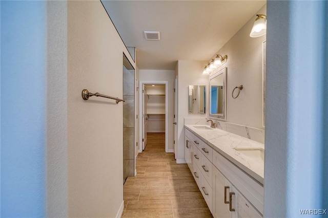 full bath featuring double vanity, a spacious closet, a sink, and visible vents