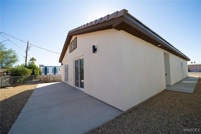 view of home's exterior with a patio area, fence, and stucco siding